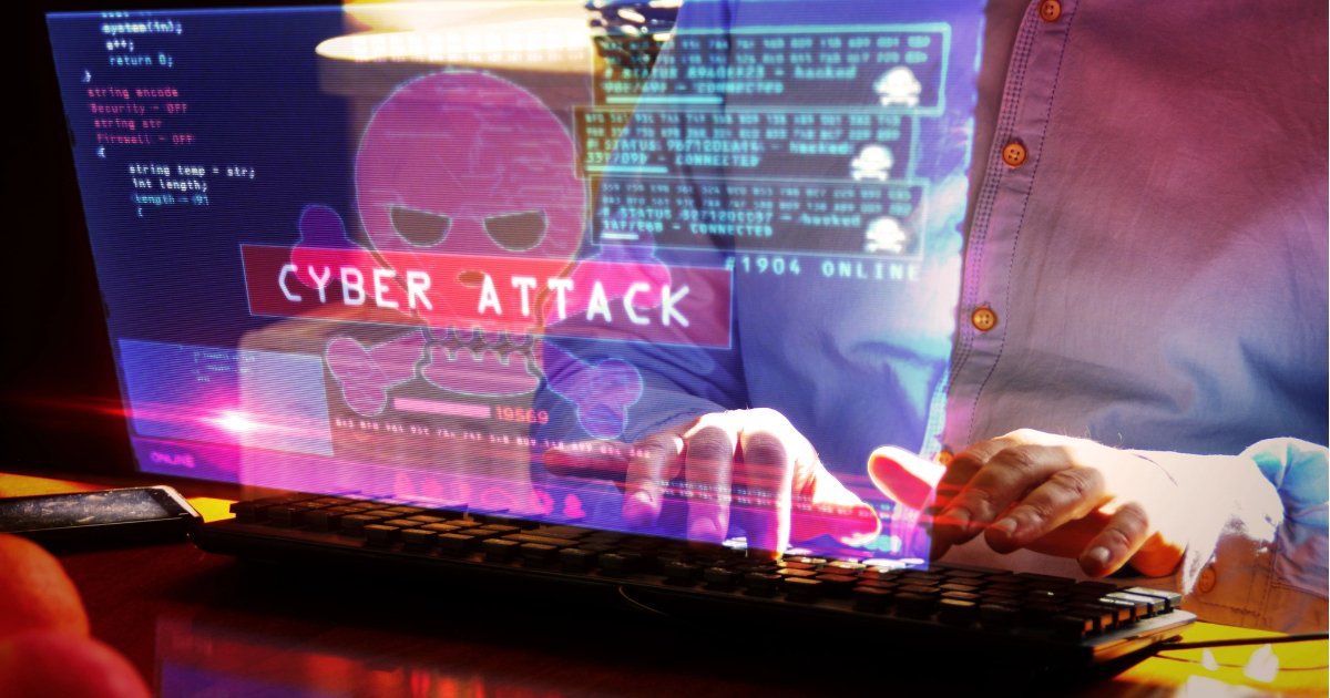 Man focused on typing at a computer keyboard with the screen displaying codes and indications of a cyber attack, highlighting the importance of cybersecurity awareness.